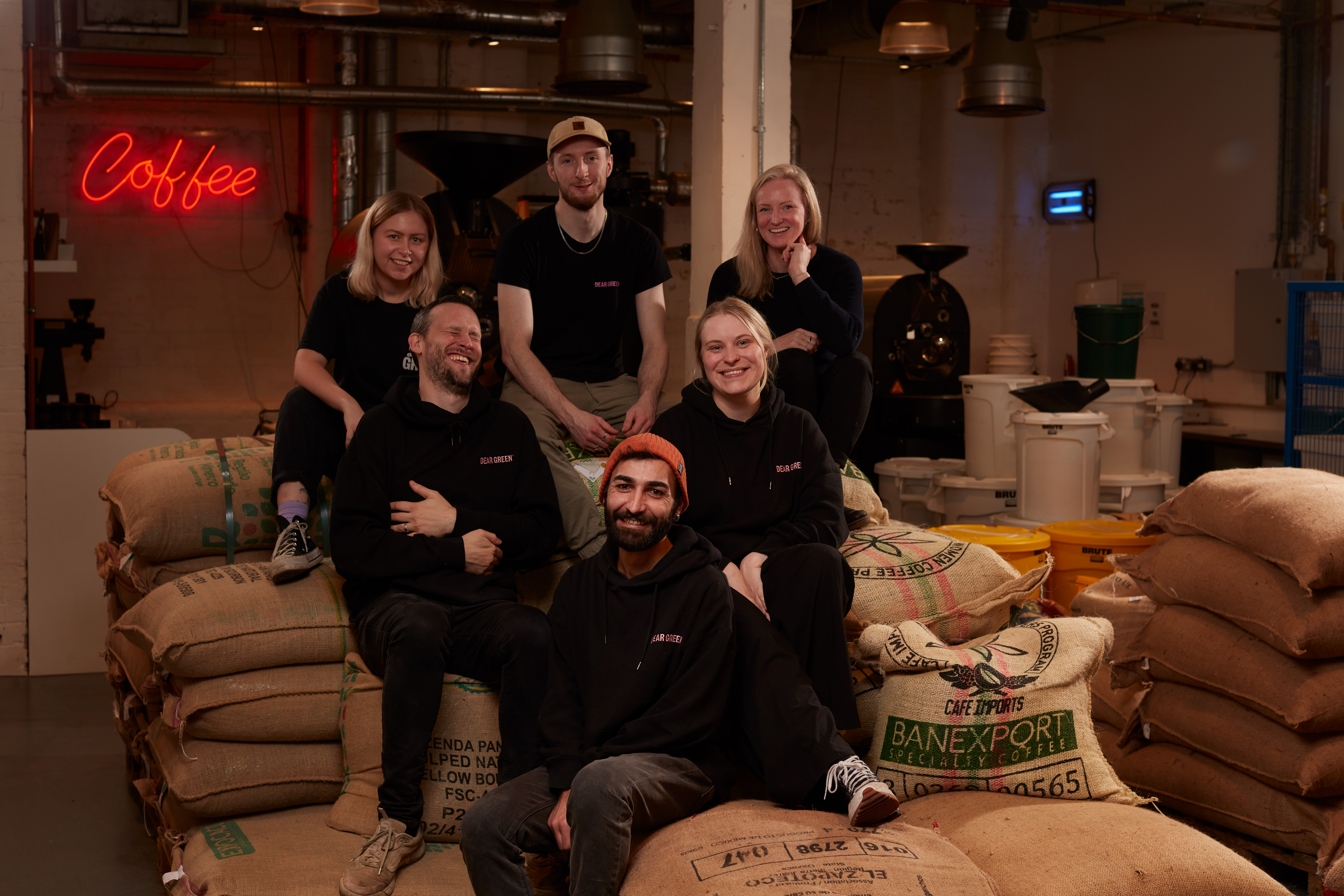 Staff posing on top of coffee bean sacks at Dear Green Coffee, Glasgow