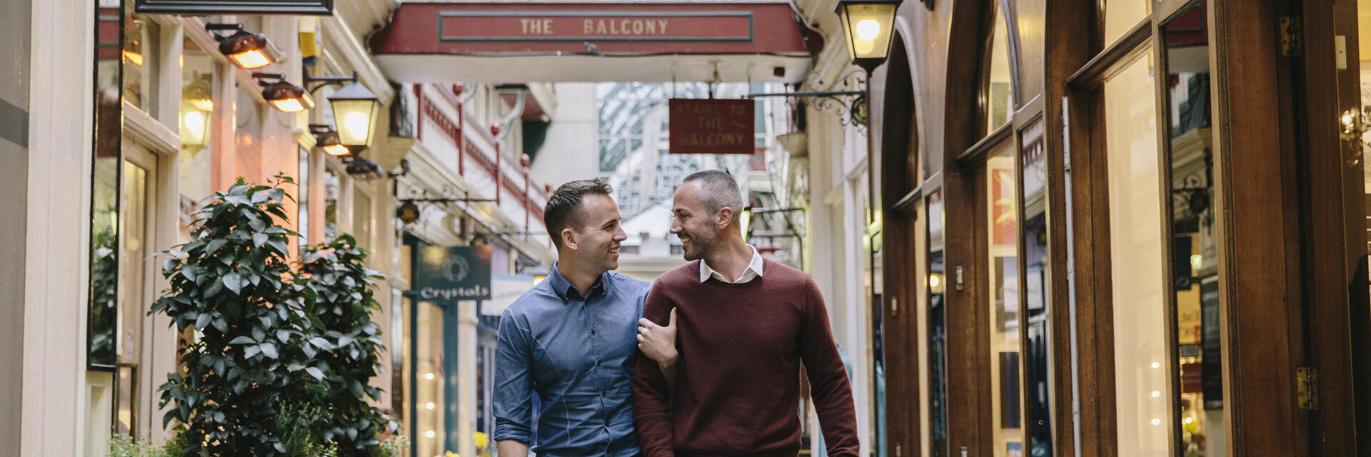 Couple d'hommes marchant bras dessus bras dessous dans une galerie marchande victorienne
