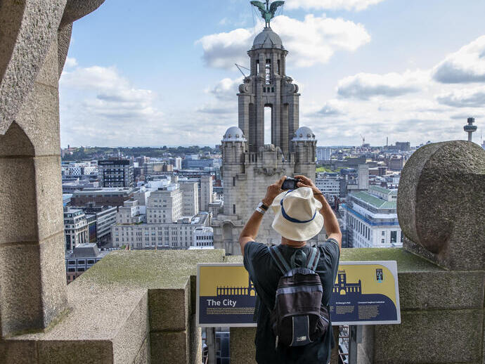 Gentleman photographing the tower in the skyline from the roof of the Royal Liver Building 360, Merseyside. 