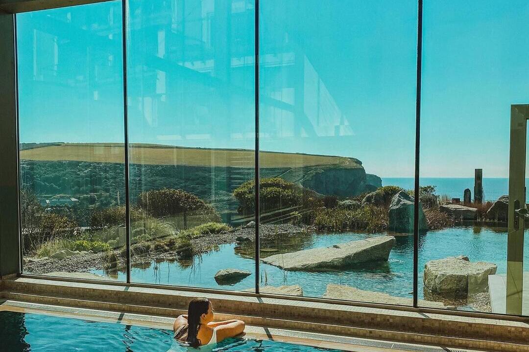 Person swimming in spa pool, surrounded by glass windows