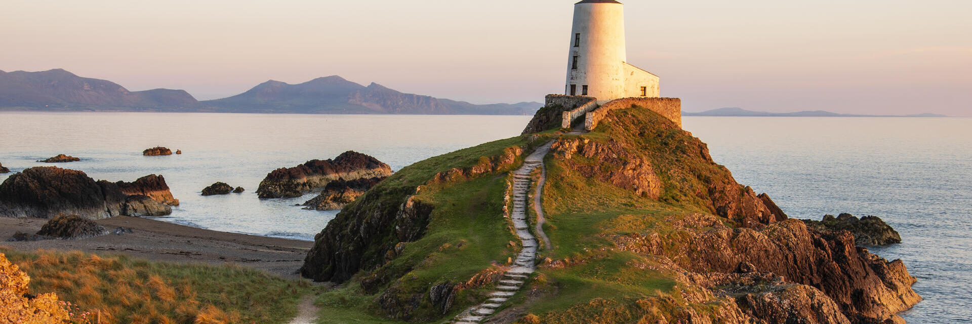 A path leading to a lighthouse on a prominent rocky outcrop by the sea