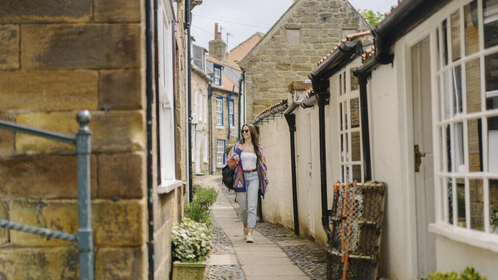 Una donna cammina lungo un pittoresco vicolo di un villaggio