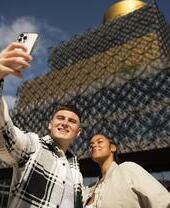 Pareja haciéndose un selfie con el móvil delante de un edificio moderno
