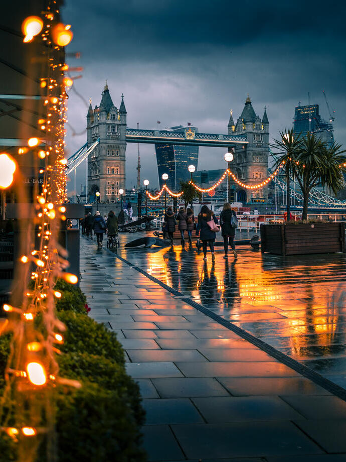 People walking past fairy lights on a city street at night