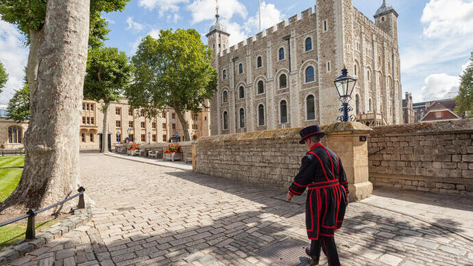 Beefeater walking by the Tower of London on a sunny day