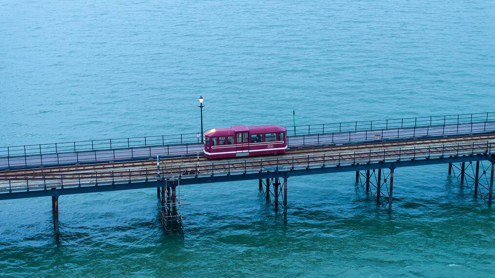 Petit train électrique circulant sur des rails au-dessus de l'océan.