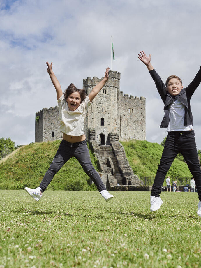 Dos niños saltando frente a un castillo.