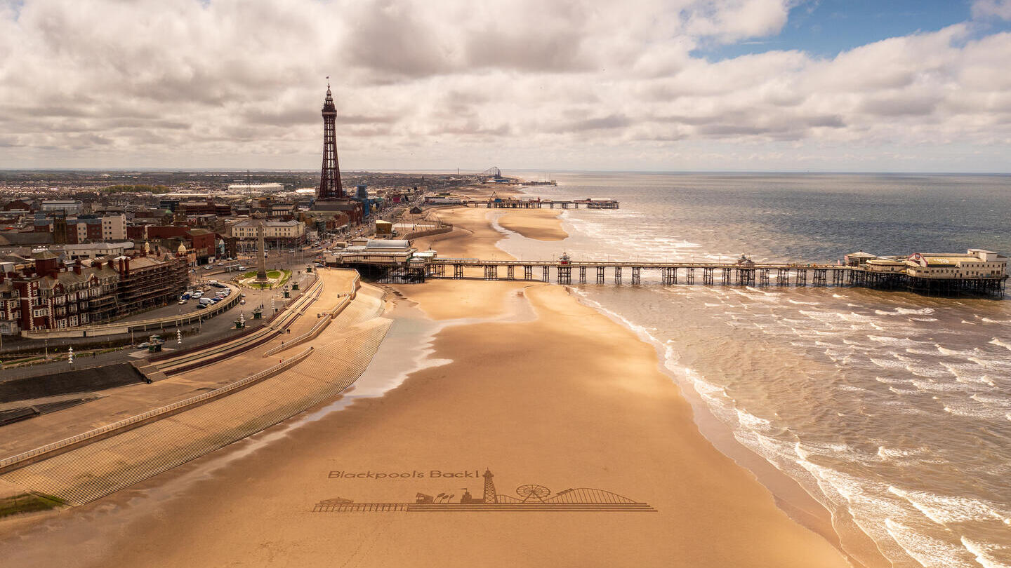 Vista panorámica de una playa de arena con un muelle y una torre.