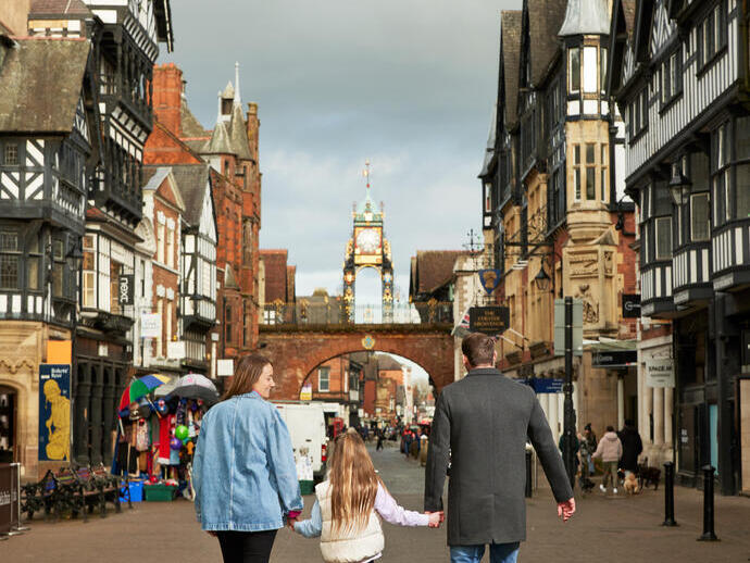 A family of three in front of the town clocktower in a shopping strip.