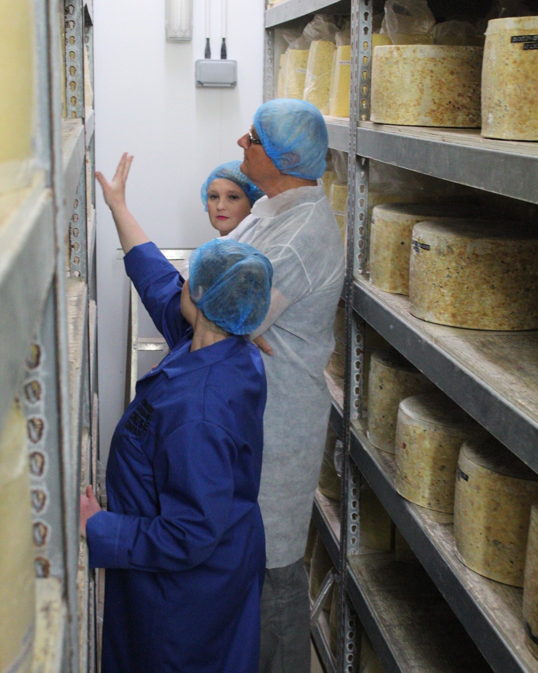 Gente mirando el queso Cheddar almacenado en una estantería