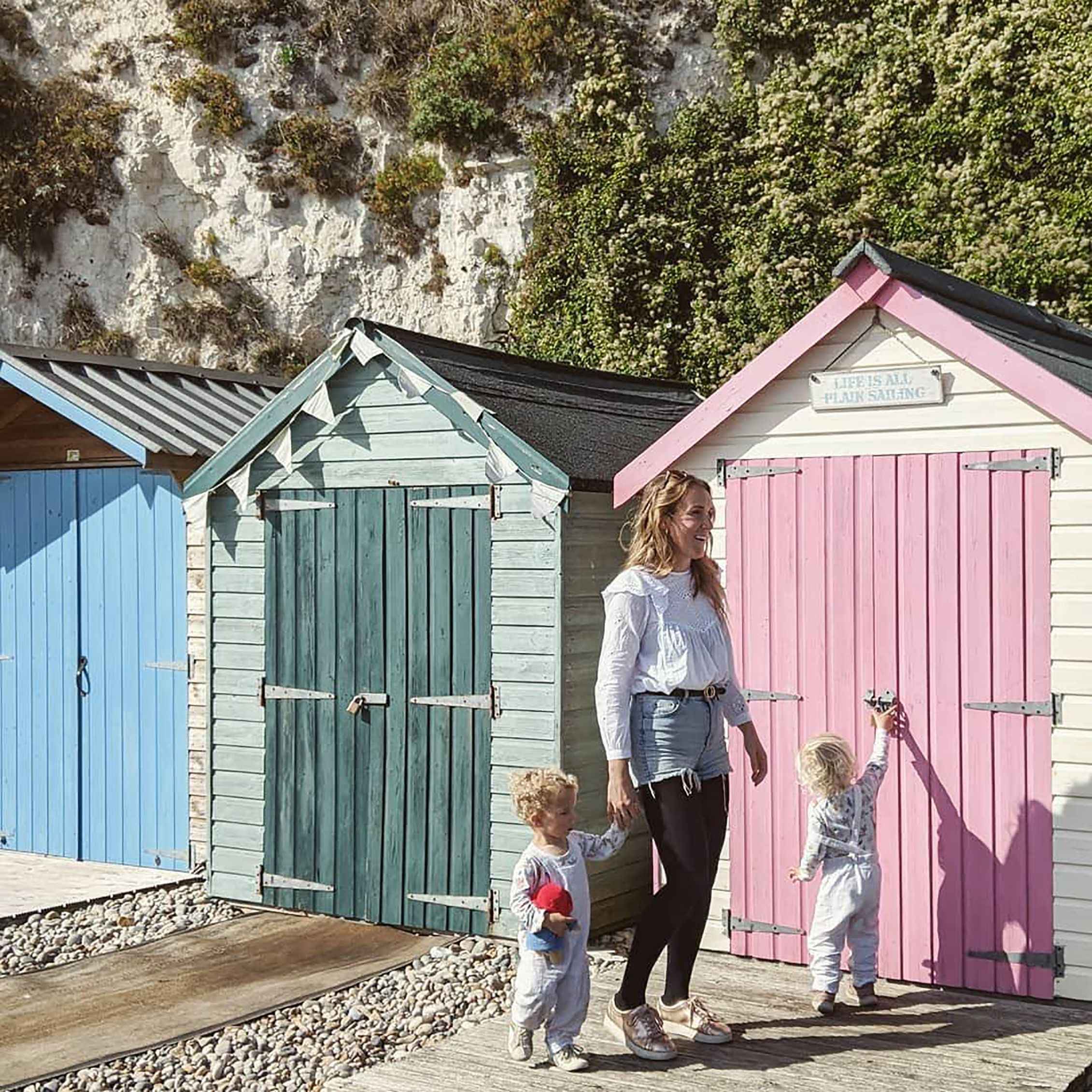 Woman and two children in front of a row of beach huts