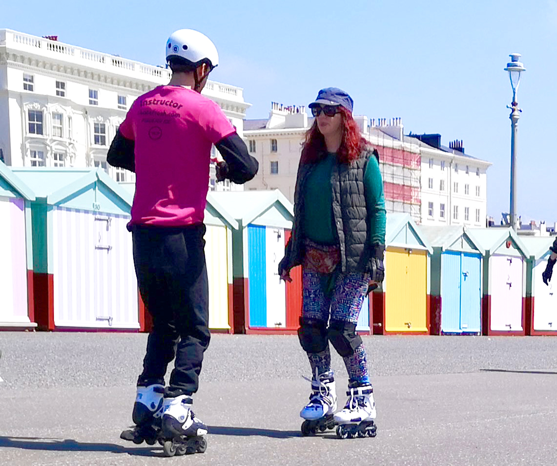 Two people rollerskating along the street in Brighton