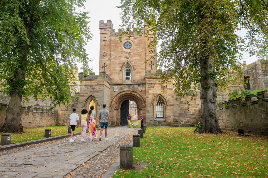 A family walking towards the gates of a castle tower