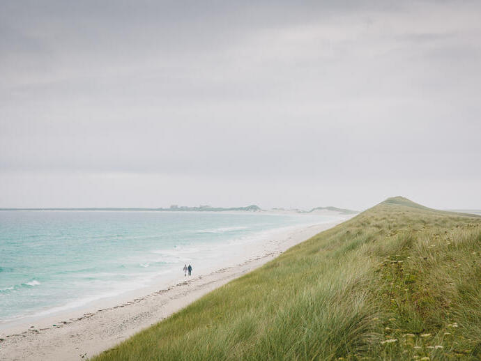 شخصان يمشيان على شاطئ كبير خالٍ من الناس، تريسنيس سانداي، أوركني