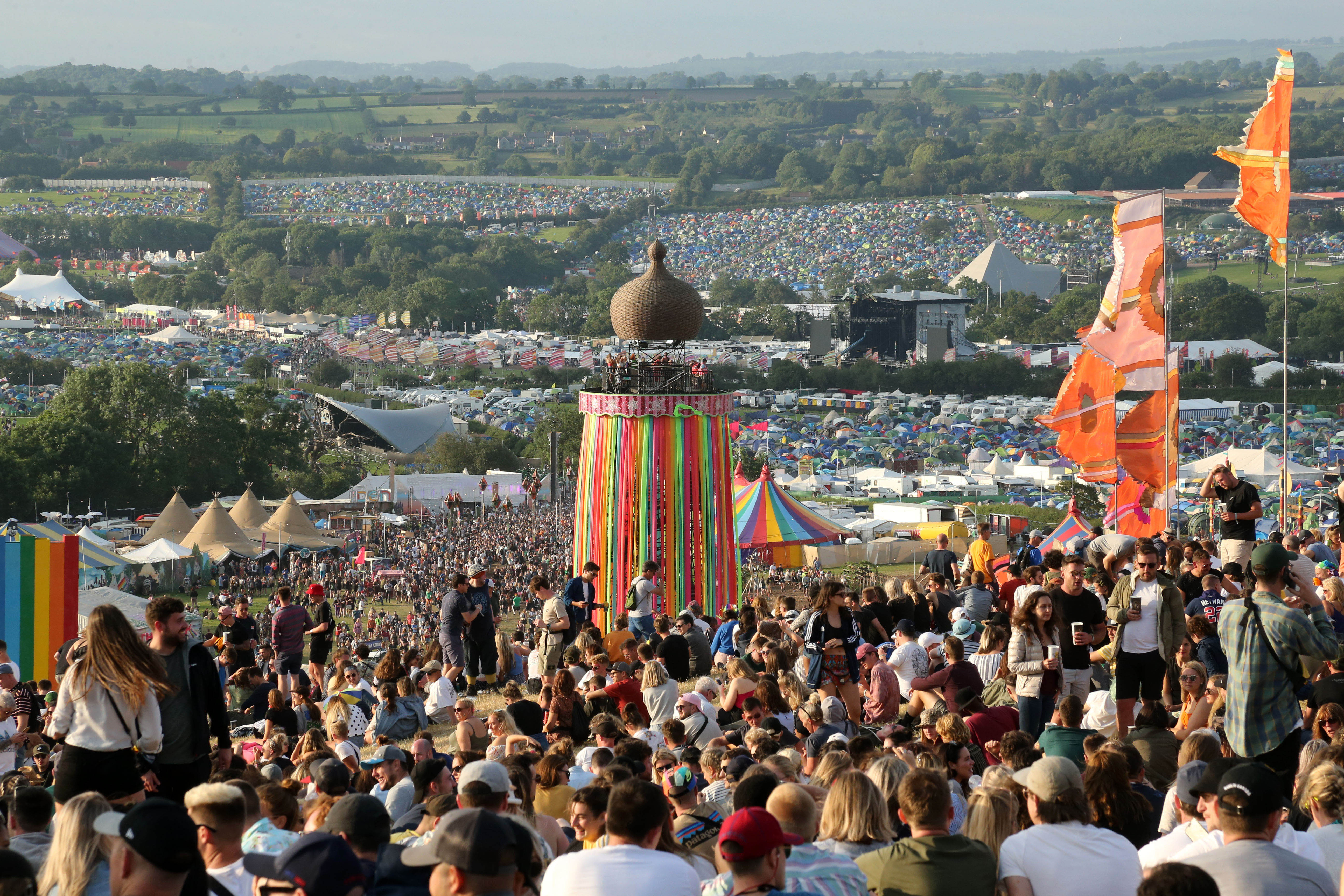 Crowd at Glastonbury Festival sitting on a hill during the day