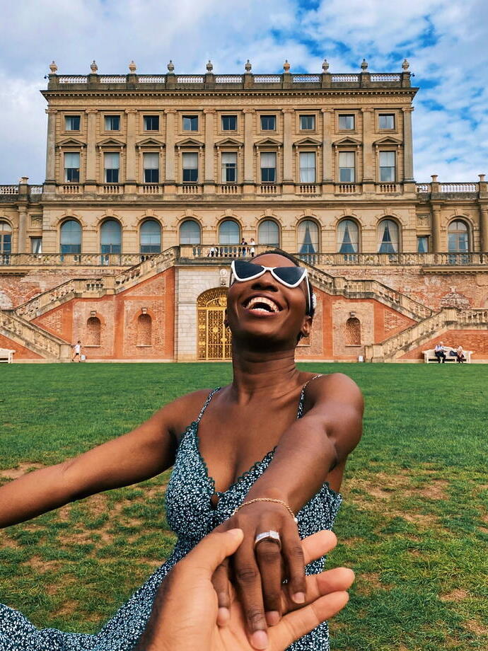 Smiling woman, wearing sunglasses and sundress, outside Cliveden Hotel
