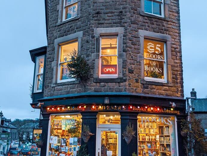 Bambino che guarda la vetrina di una libreria illuminata dalla luce della sera