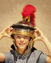 Child wearing a Roman Centurion helmet with a red feather