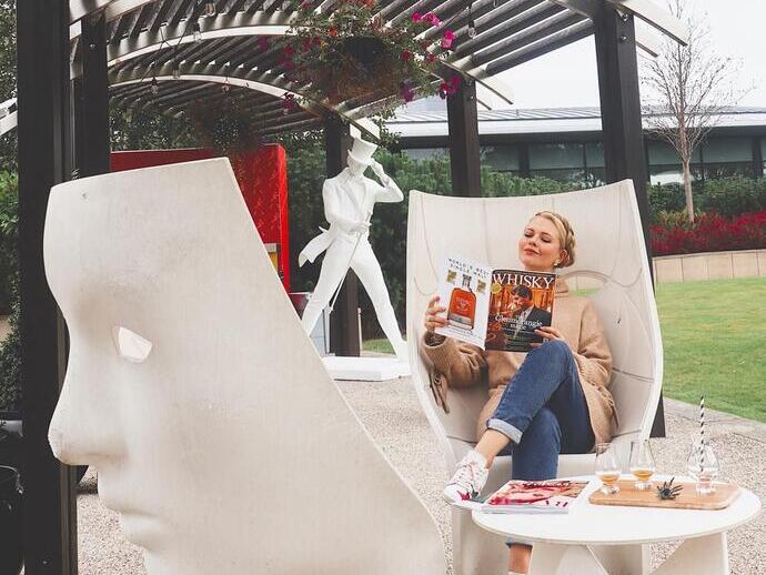 A woman sitting down reading a magazine, outside The Glasshouse, Edinburgh, Scotland