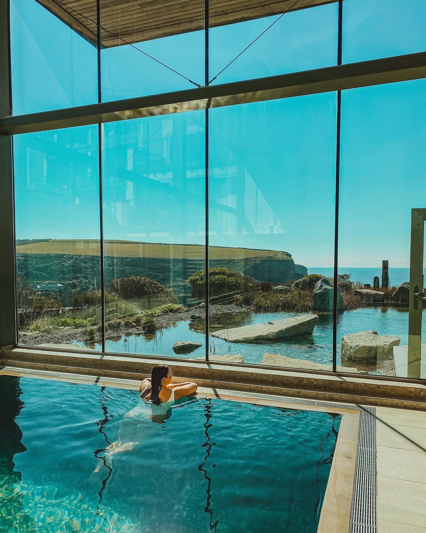 Person swimming in spa pool, surrounded by glass windows