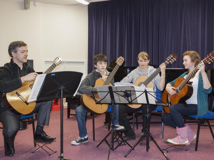 A group of people preparing to play guitars on stage as part of Oxford Music Festival