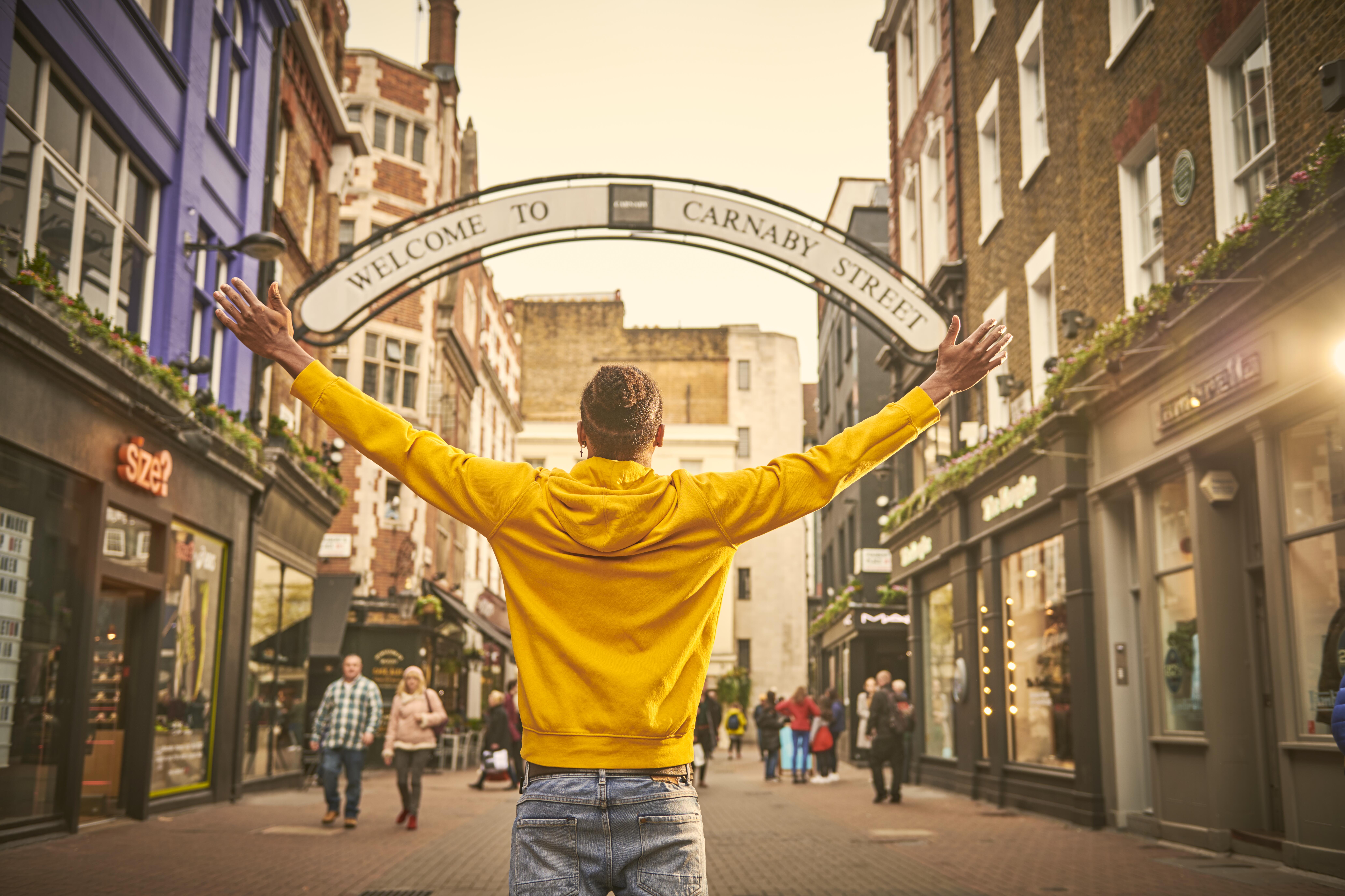 Man standing with arms outstretched on a street