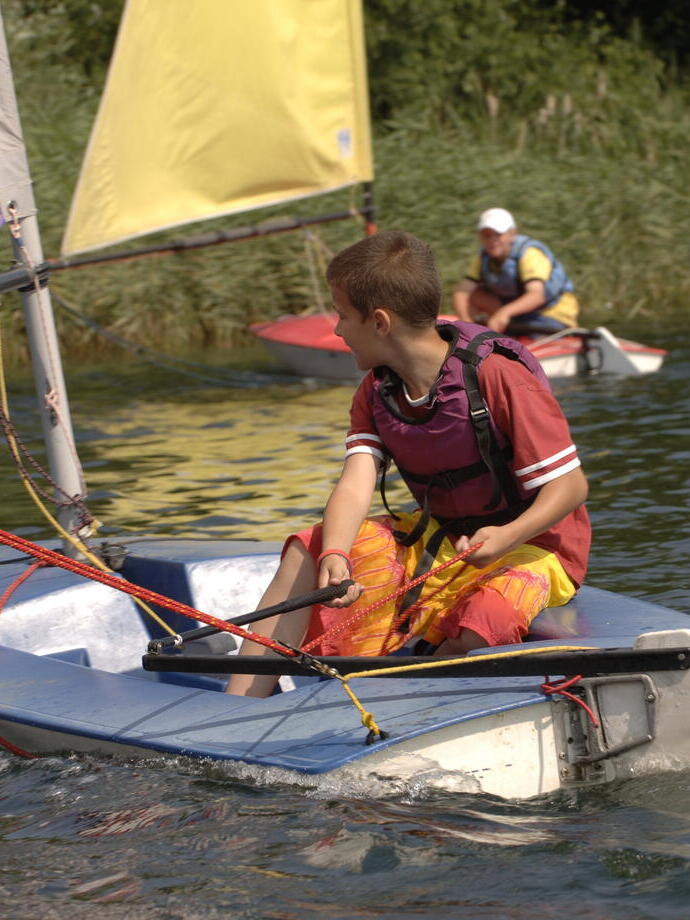 A child sailing a boat on a river in the Broads National Park