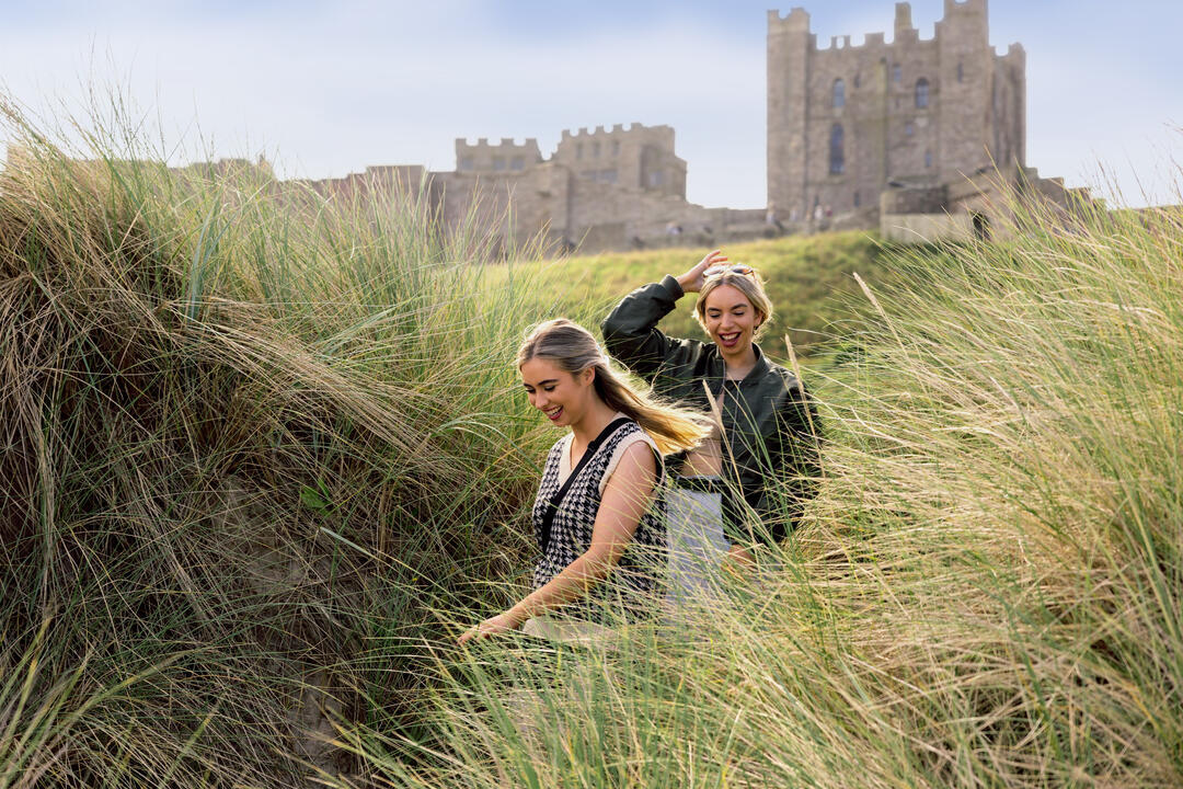 A couple walking in the sand dunes near Bamburgh Castle