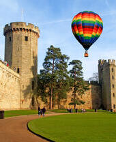 Un globo aerostático flota sobre un castillo y sus cuidados jardines.