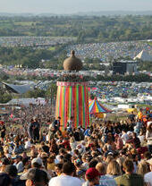 Crowd at Glastonbury Festival sitting on a hill during the day
