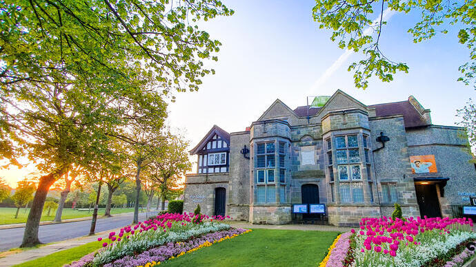 Maison historique entourée d'arbres et d'un jardin en fleurs