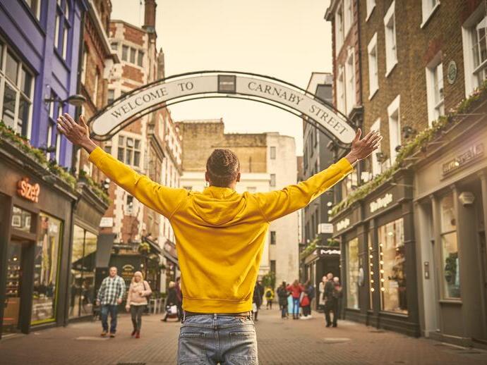 Man standing with arms outstretched on a street