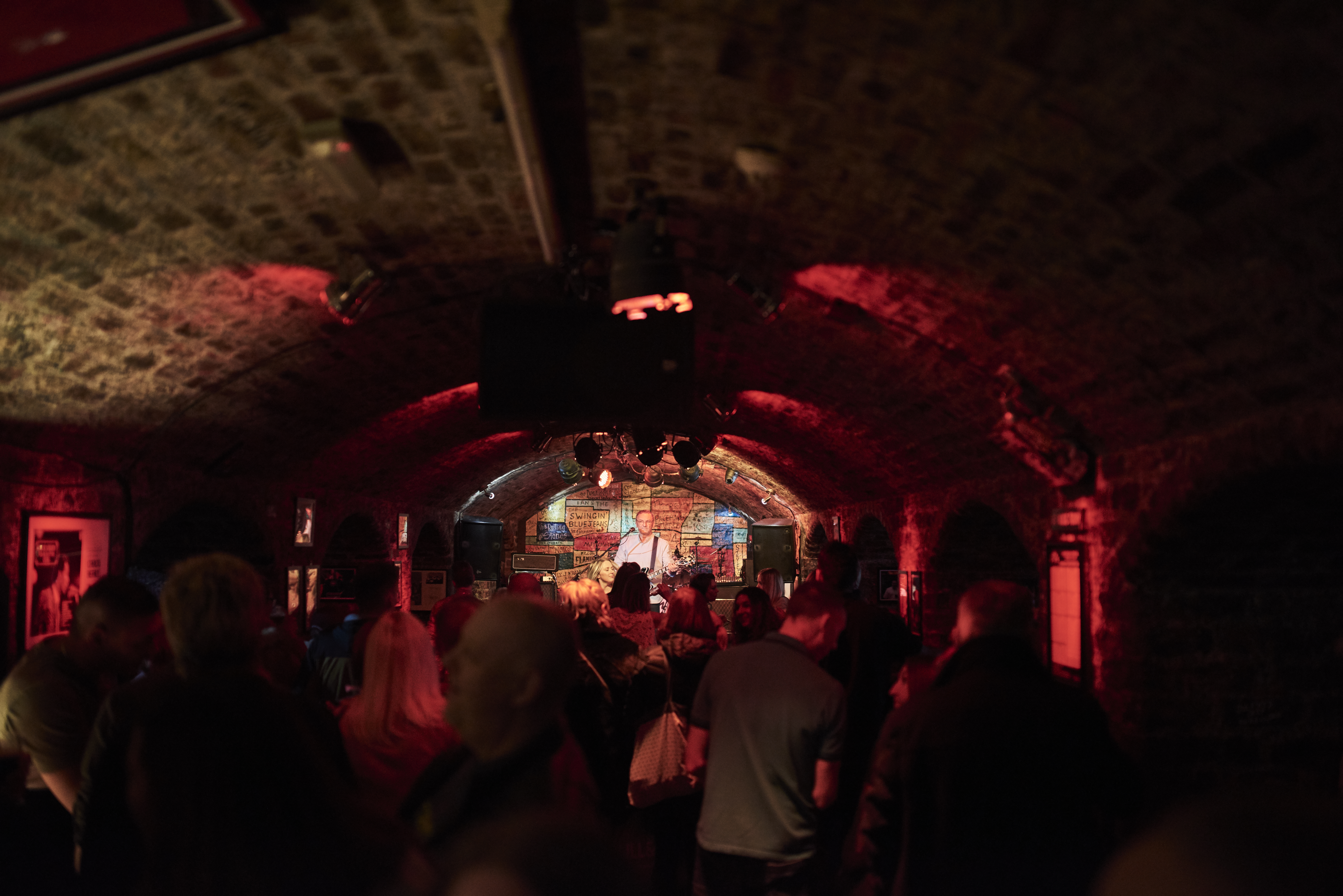 Brick tunnel-shaped room with music act on stage.