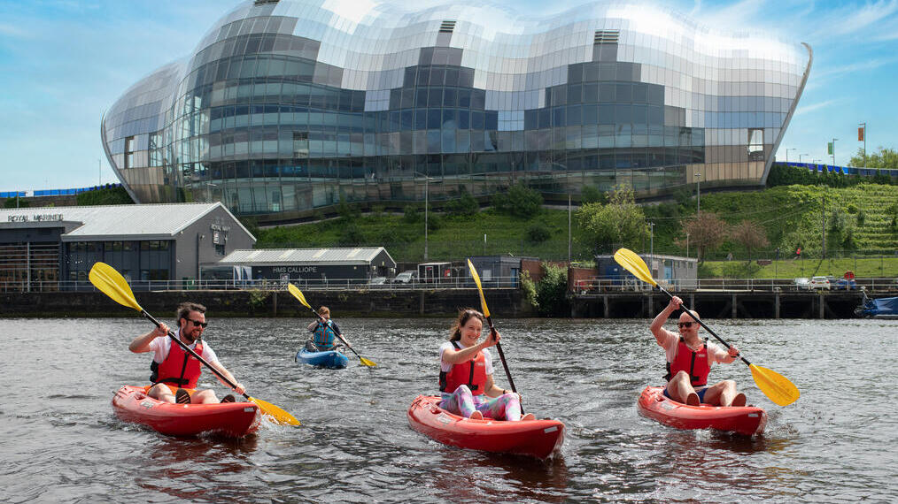 A group of people kayaking in front of an iconic building