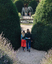Couple arm in arm walking through formal gardens