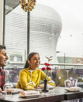 Three young people sat at a dining table with high views