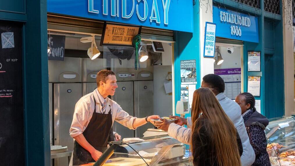 A fishmonger serving a customer at Grainger Market in Newcastle