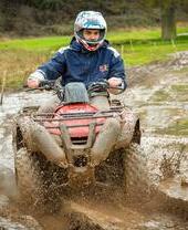 Un hombre montando en quad por un camino embarrado