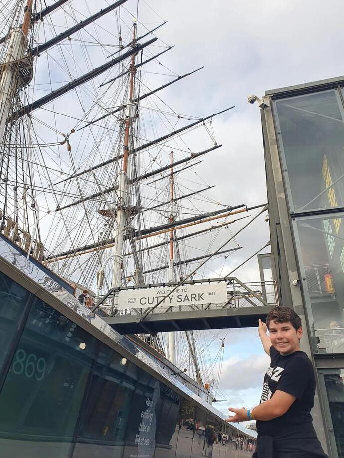 Ein Kind posiert vor der Cutty Sark in Greenwich, London