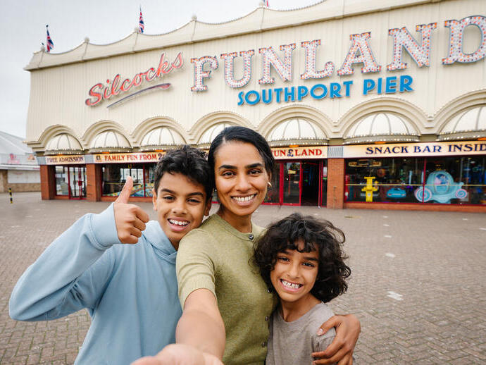 A mother and two sons stand outside an amusement park
