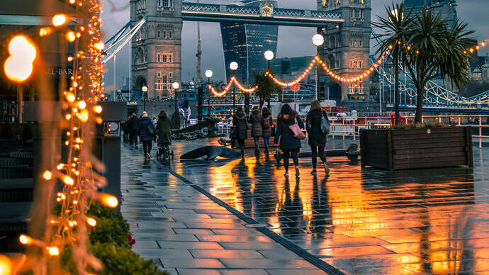 People walking past fairy lights on a city street at night