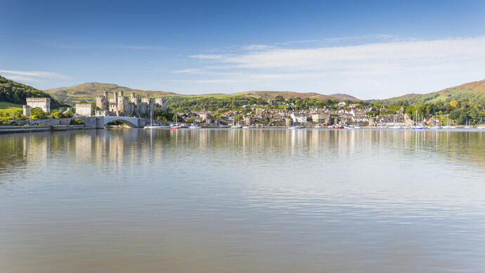 A view of a lake an village with an old castle in the background.