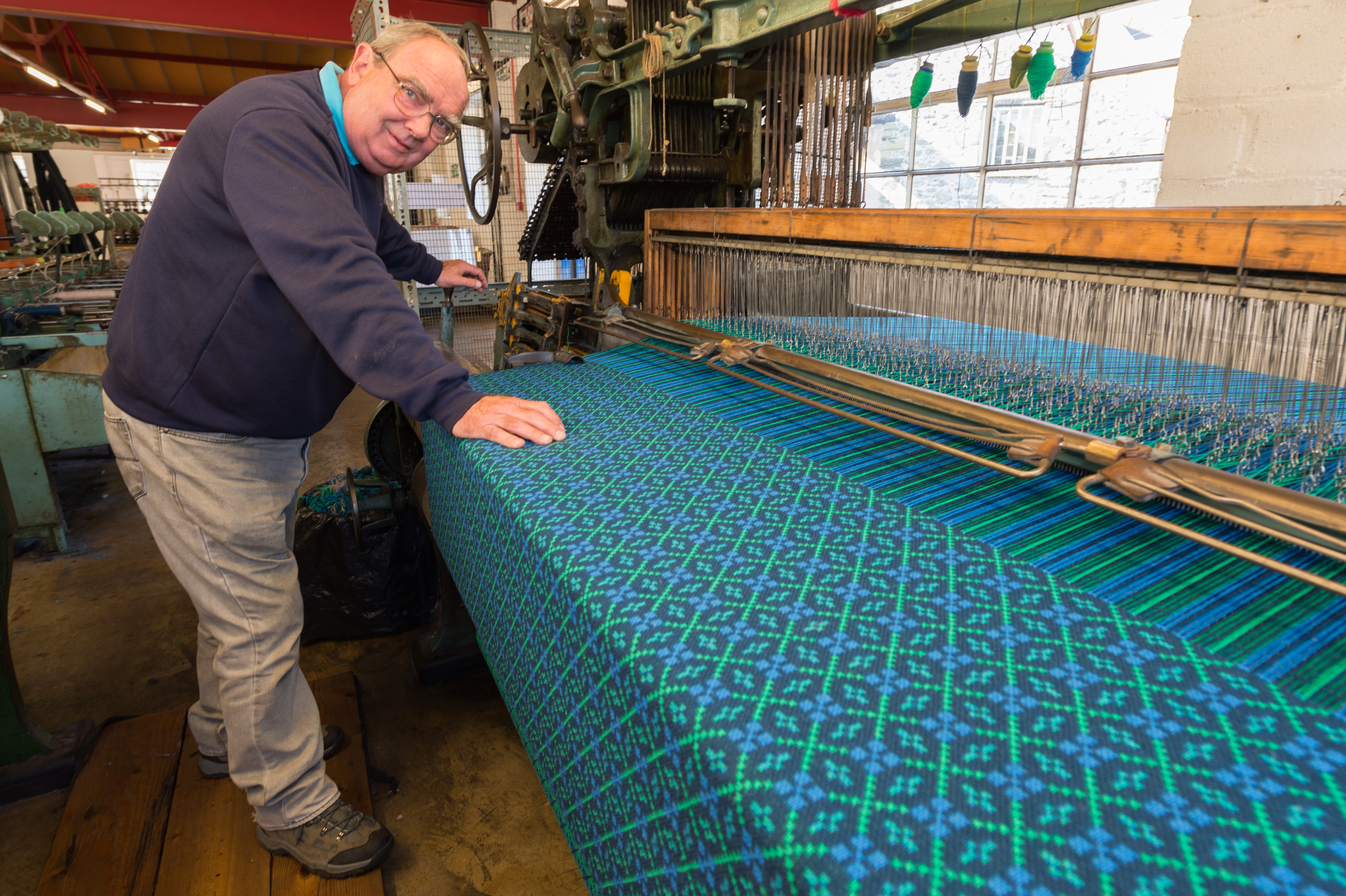 A weaver displaying a working weaving loom at Trefriw Woolen Mills in Snowdonia/Eryri National Park, Wales