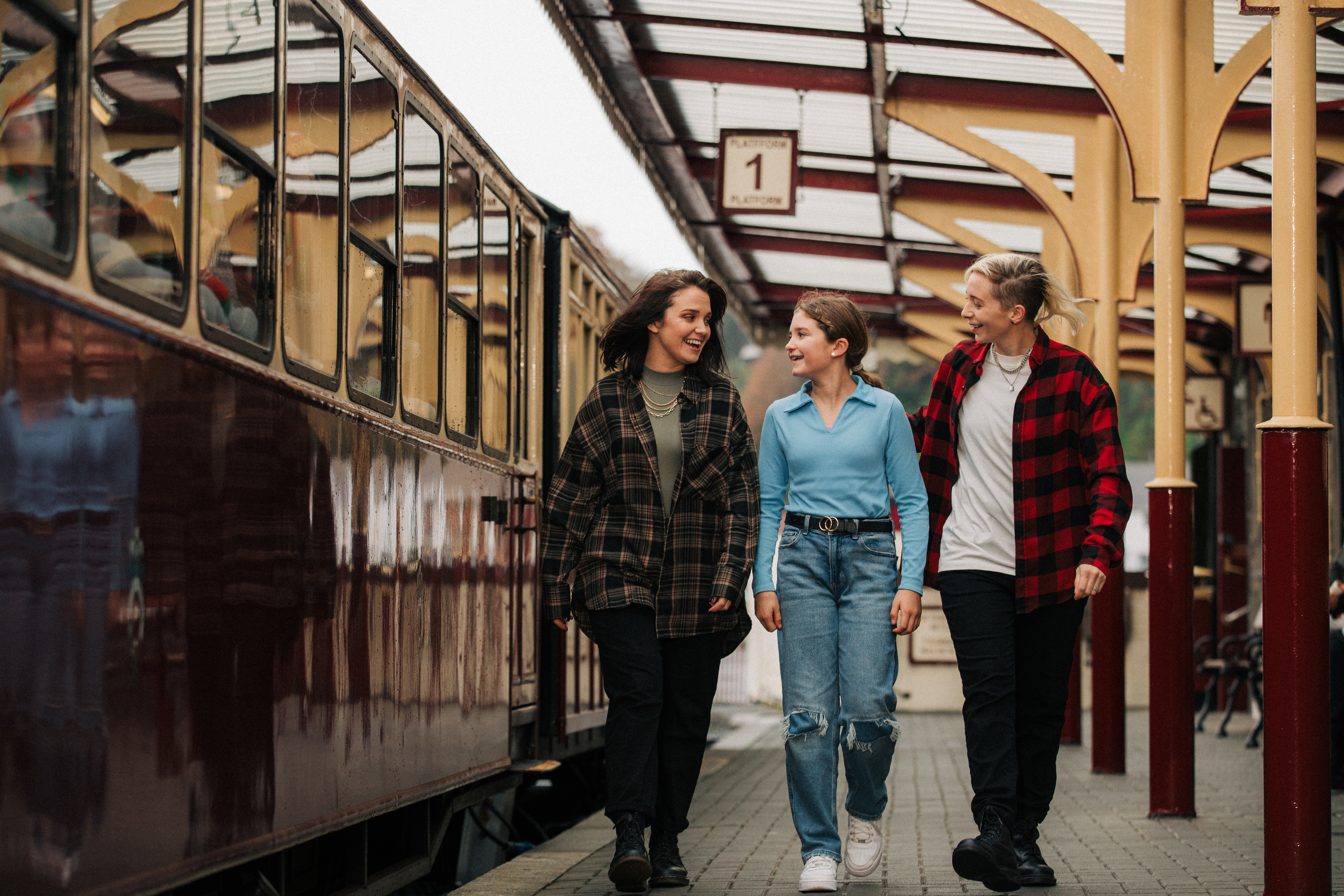 Three people walking along a train platform.