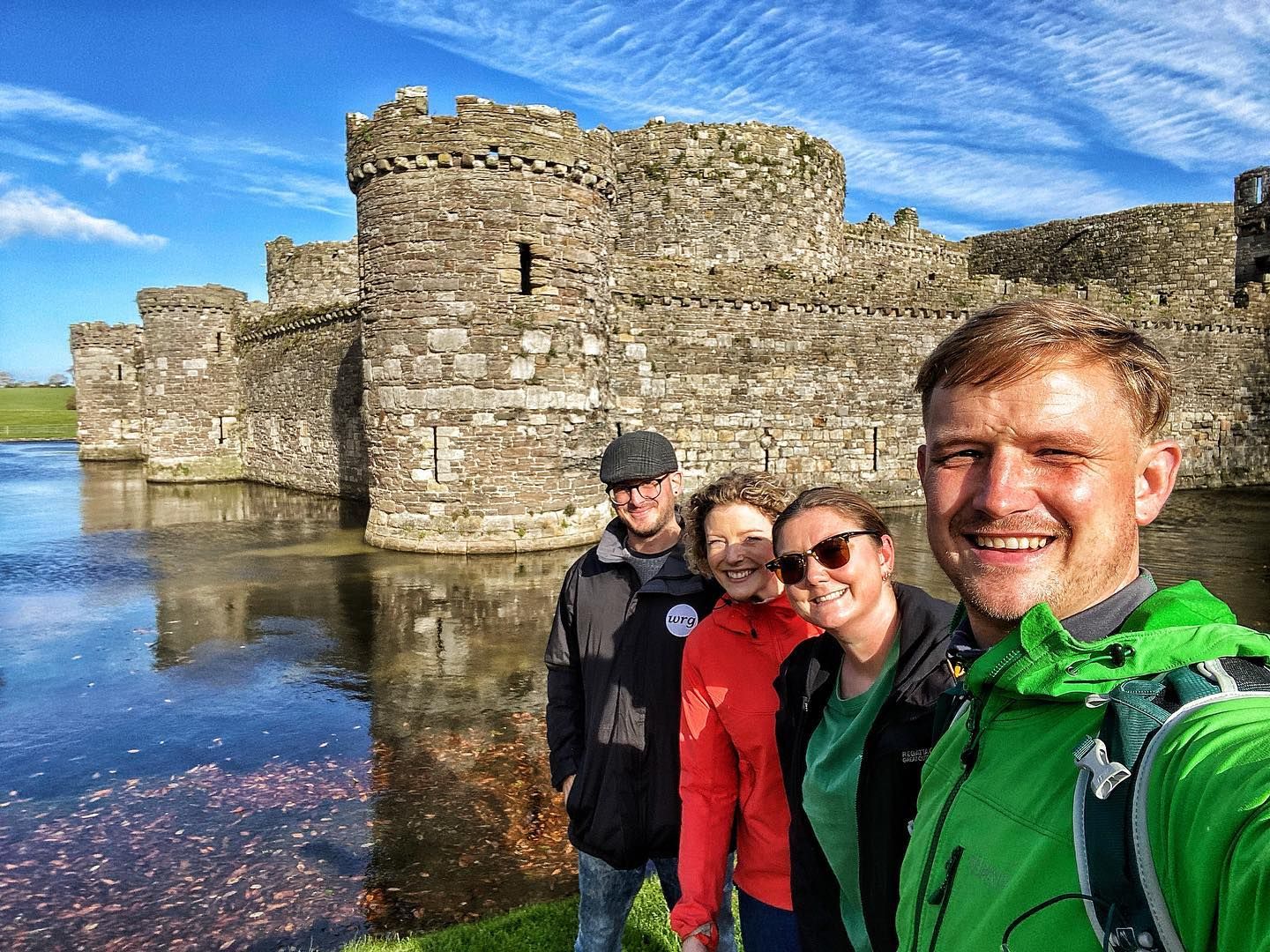 A group of people posing by the water near Beaumaris Castle in Wales