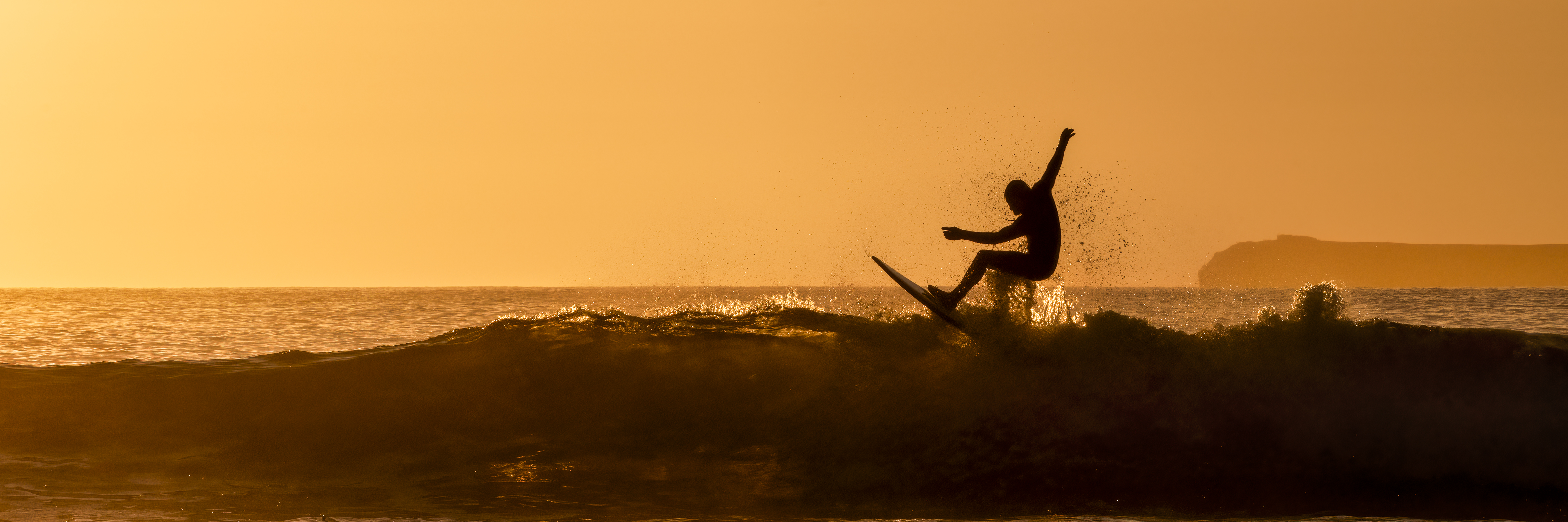 Silhouette man surfing in sea at sunset.