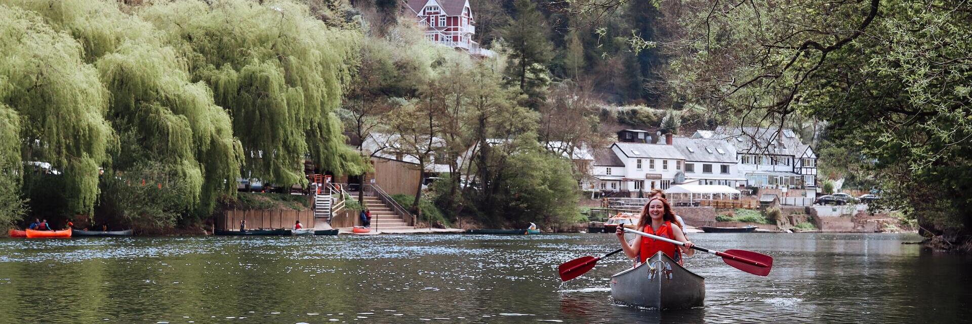 A woman in a canoe with hills and buildings behind
