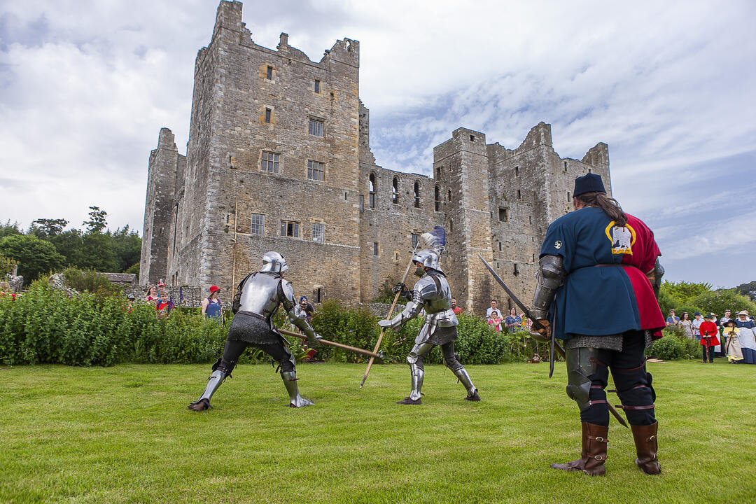 Two men in full knight armor putting on a performance for a watching crowd at Bolton Castle, Yorkshire