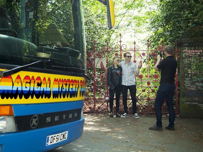 People pose for photo in front of gates on the Magical Mystery Tour in Liverpool