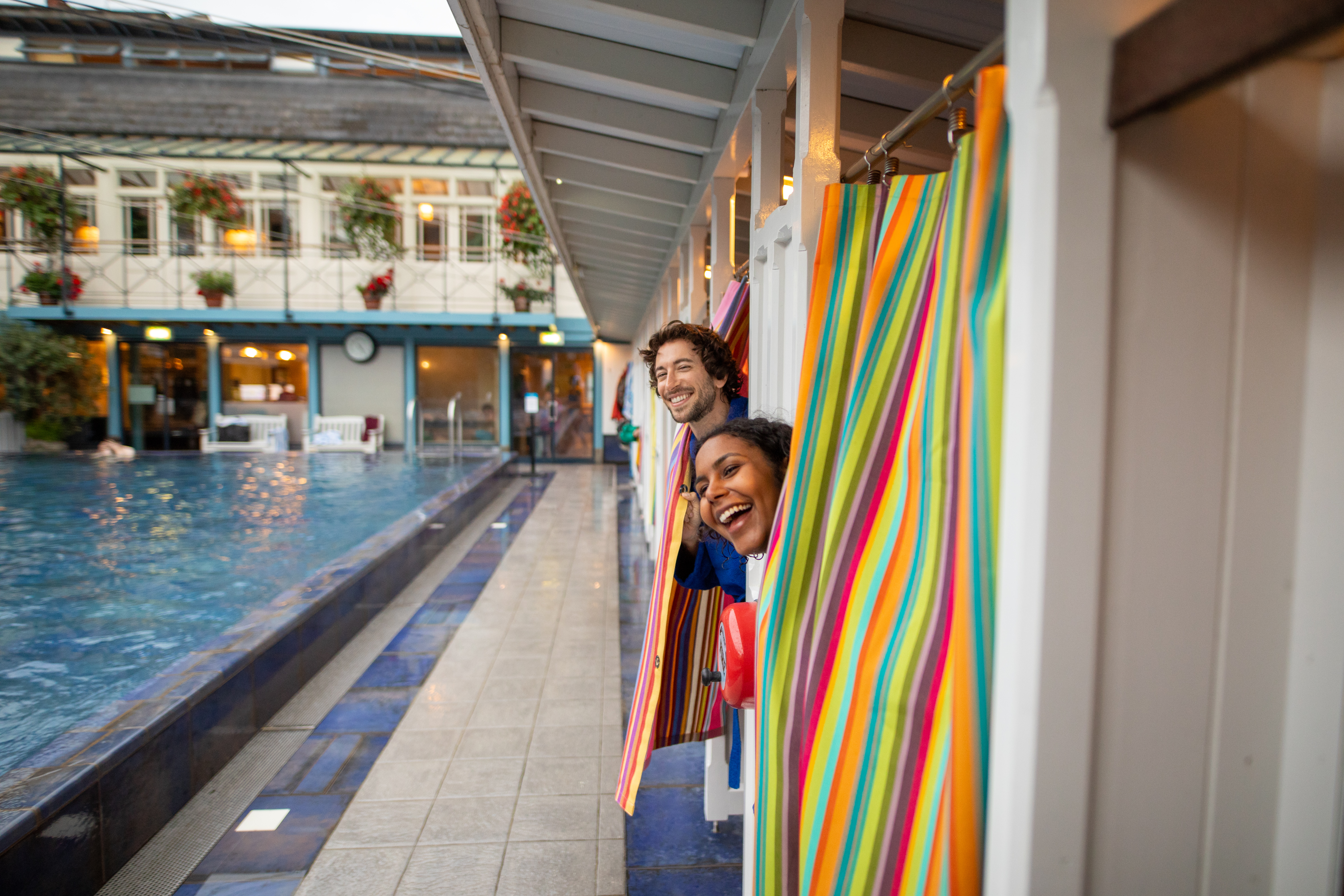 Man and woman peek out of changing rooms before going for a swim